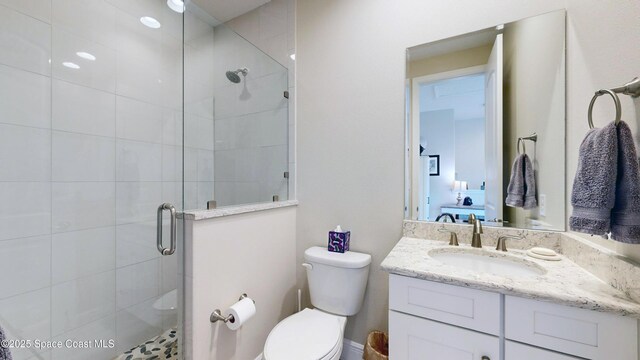 bathroom with a shower stall, toilet, and vanity