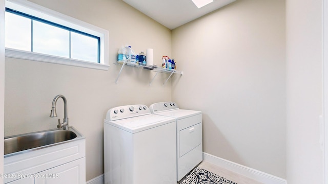 clothes washing area featuring a sink, baseboards, washing machine and dryer, and laundry area