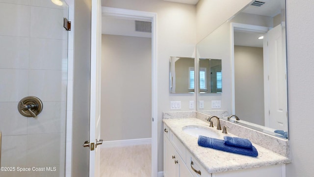 full bathroom featuring visible vents, baseboards, vanity, and a tile shower