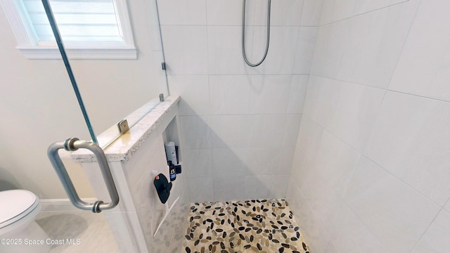 full bath featuring toilet and a tile shower