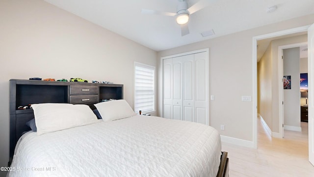 bedroom featuring a closet, light wood-style flooring, baseboards, and ceiling fan