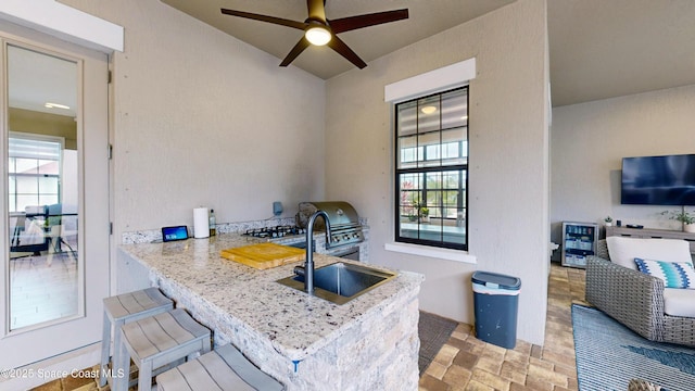 kitchen with ceiling fan, stone finish floor, and a sink