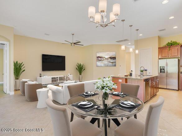 tiled dining space featuring ceiling fan with notable chandelier and sink