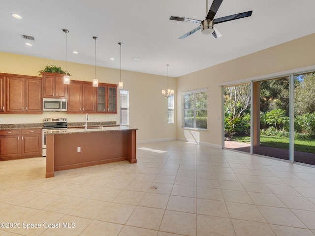 kitchen featuring light tile patterned flooring, decorative light fixtures, sink, stainless steel appliances, and light stone countertops