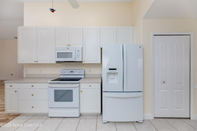 kitchen featuring light tile patterned floors, white cabinets, and white appliances