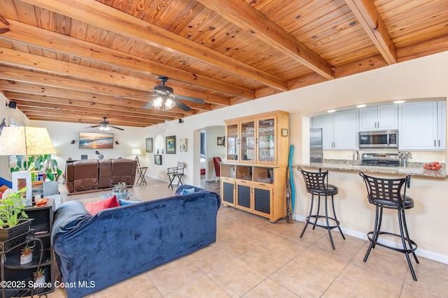 living room with ceiling fan, wooden ceiling, and beam ceiling