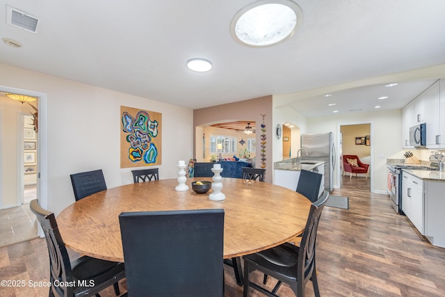 dining area featuring sink, wood-type flooring, and ceiling fan