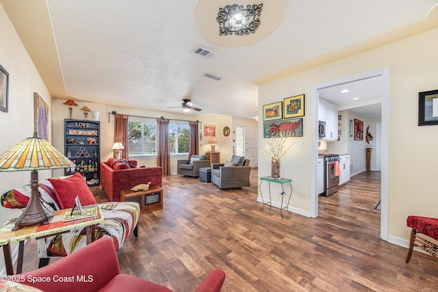 living room with ceiling fan, dark hardwood / wood-style floors, and a textured ceiling