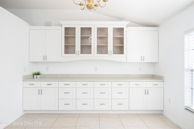 kitchen with white cabinetry, light tile patterned flooring, and vaulted ceiling