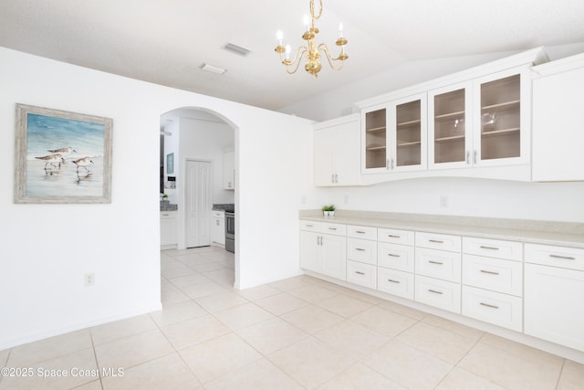 kitchen with pendant lighting, stainless steel range, vaulted ceiling, and white cabinets