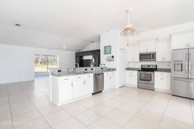 kitchen featuring vaulted ceiling, white cabinets, kitchen peninsula, stainless steel appliances, and light stone countertops