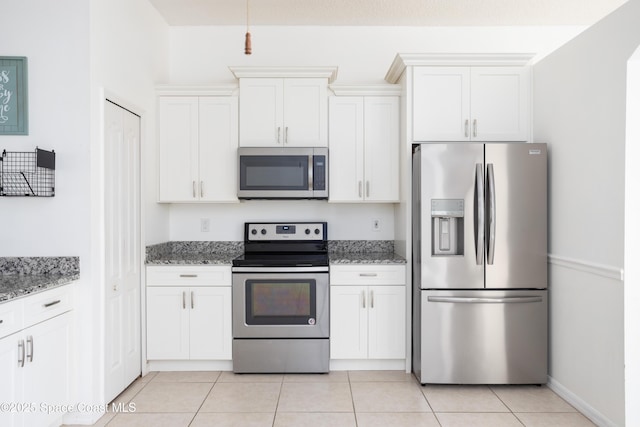 kitchen with stone counters, white cabinetry, appliances with stainless steel finishes, and light tile patterned floors