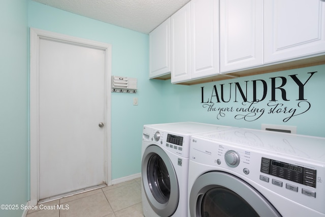 laundry room with cabinets, washing machine and dryer, a textured ceiling, and light tile patterned floors