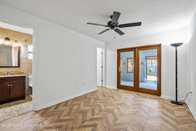 interior space with sink, access to outside, light parquet flooring, a textured ceiling, and french doors