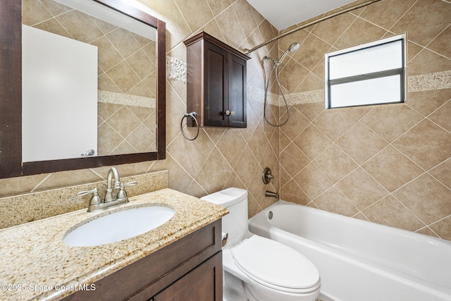 full bathroom featuring vanity, tiled shower / bath combo, tile walls, and toilet