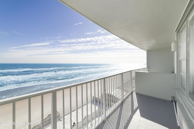 balcony with a water view and a view of the beach