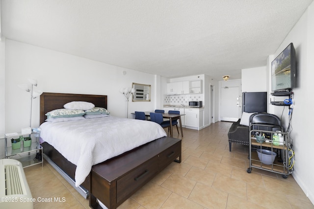 bedroom with light tile patterned floors, a textured ceiling, and refrigerator