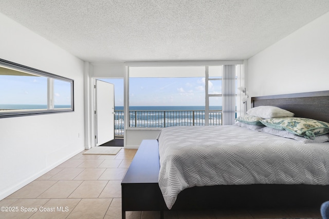 bedroom with light tile patterned floors, a textured ceiling, access to exterior, and a water view