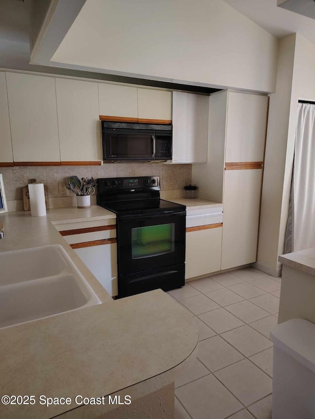 kitchen featuring light tile patterned floors, decorative backsplash, black appliances, and white cabinets