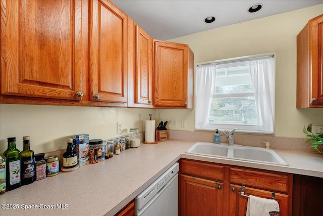 kitchen featuring dishwasher, light countertops, brown cabinetry, and a sink