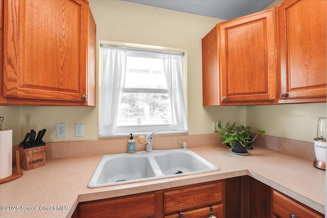 kitchen with light countertops, brown cabinetry, and a sink