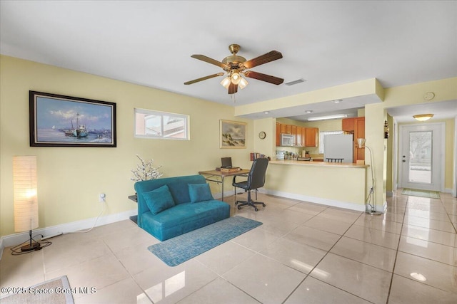 interior space with baseboards, visible vents, ceiling fan, and light tile patterned flooring