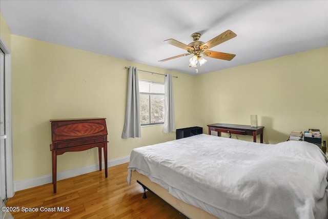 bedroom with ceiling fan, baseboards, and wood finished floors