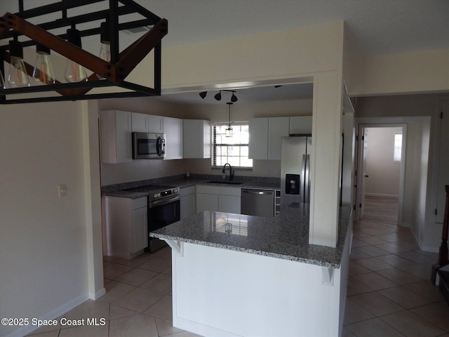 kitchen featuring light tile patterned floors, appliances with stainless steel finishes, white cabinetry, a kitchen breakfast bar, and decorative light fixtures