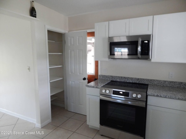 kitchen with light tile patterned floors, stainless steel appliances, and white cabinets