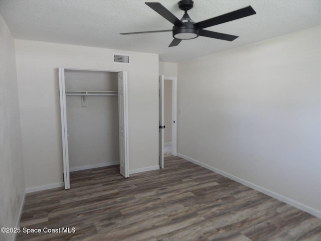 unfurnished bedroom featuring dark wood-type flooring, ceiling fan, and a closet