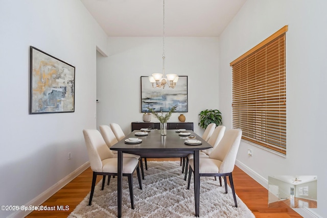 dining space with hardwood / wood-style flooring and a chandelier