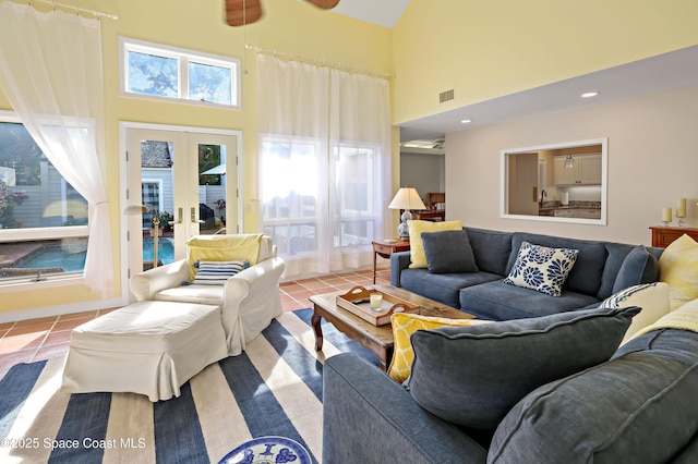 tiled living room with french doors, ceiling fan, and a high ceiling