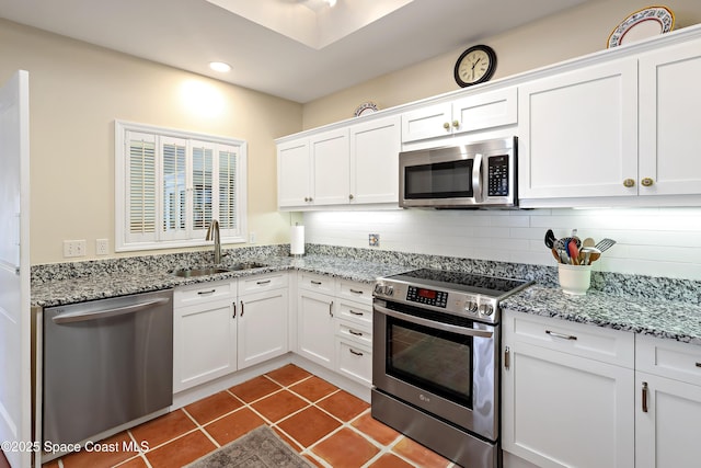 kitchen with dark tile patterned floors, appliances with stainless steel finishes, sink, and white cabinets