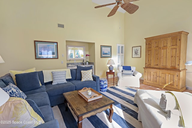 living room with ceiling fan, a towering ceiling, and light tile patterned floors