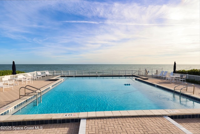 view of pool with a patio area and a water view