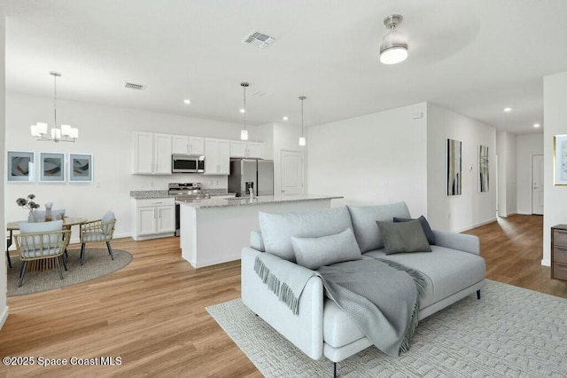 living room with light hardwood / wood-style flooring and a chandelier