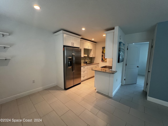 kitchen with white cabinetry, sink, dark stone countertops, and stainless steel refrigerator with ice dispenser