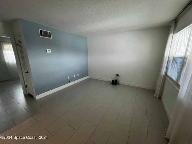 unfurnished room with a textured ceiling