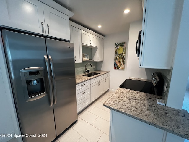 kitchen featuring sink, white cabinetry, light stone counters, stainless steel fridge, and stove