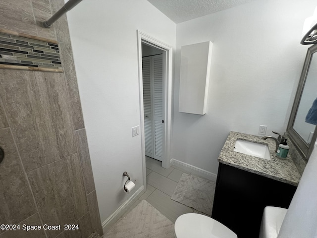 bathroom with tile patterned floors, vanity, toilet, and a textured ceiling