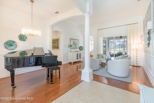 interior space featuring ornamental molding, light hardwood / wood-style flooring, and ornate columns