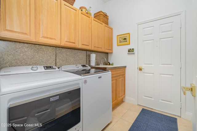 laundry room with cabinets, sink, light tile patterned floors, and washer and clothes dryer