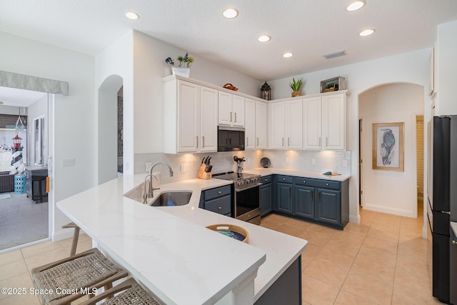 kitchen featuring stainless steel range with electric stovetop, sink, kitchen peninsula, and white cabinets