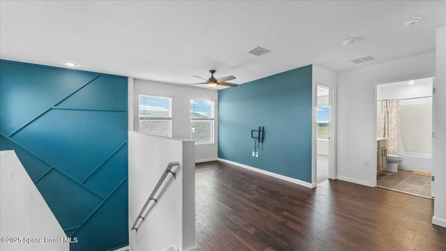 empty room featuring dark wood-type flooring, ceiling fan, and a textured ceiling