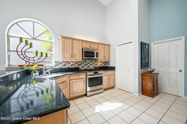 kitchen featuring sink, tasteful backsplash, dark stone countertops, light brown cabinets, and appliances with stainless steel finishes