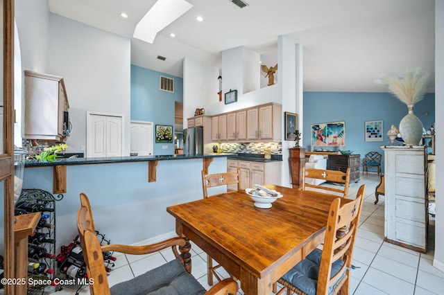 tiled dining room with high vaulted ceiling and a skylight