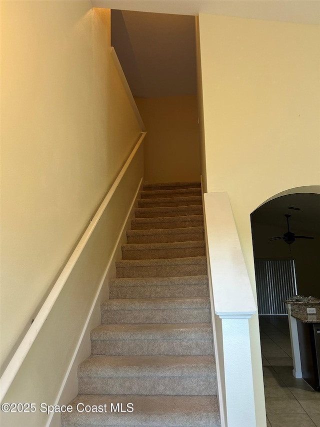 stairway with tile patterned floors and ceiling fan