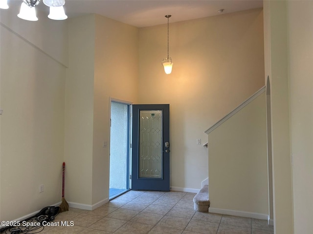 tiled entryway with a towering ceiling and a chandelier