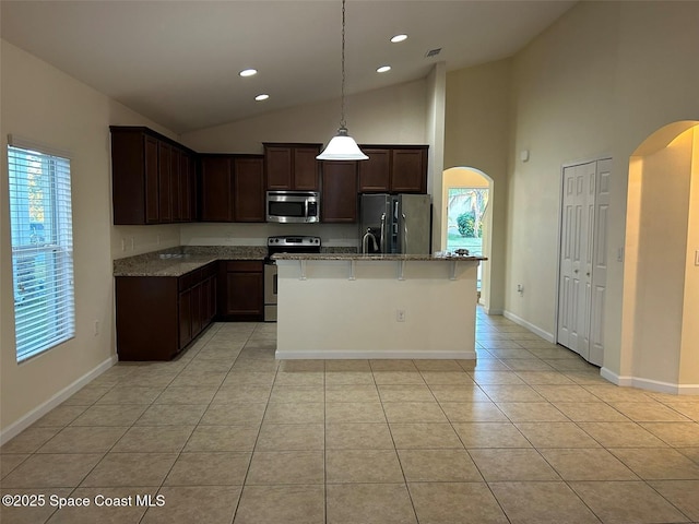 kitchen with light tile patterned floors, a kitchen island with sink, stainless steel appliances, a healthy amount of sunlight, and decorative light fixtures