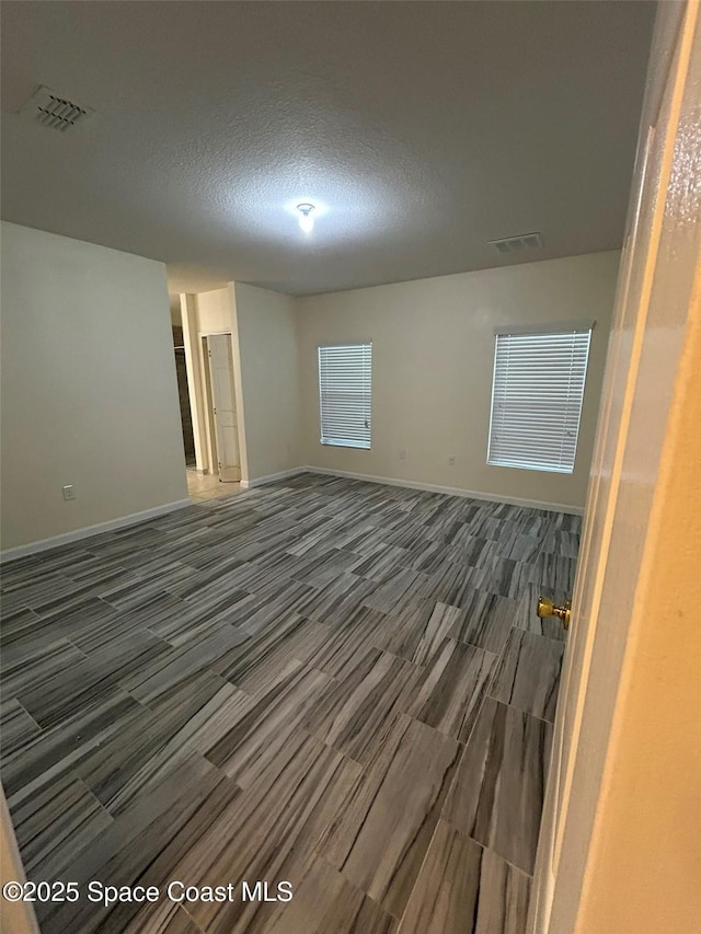 spare room with dark hardwood / wood-style flooring and a textured ceiling